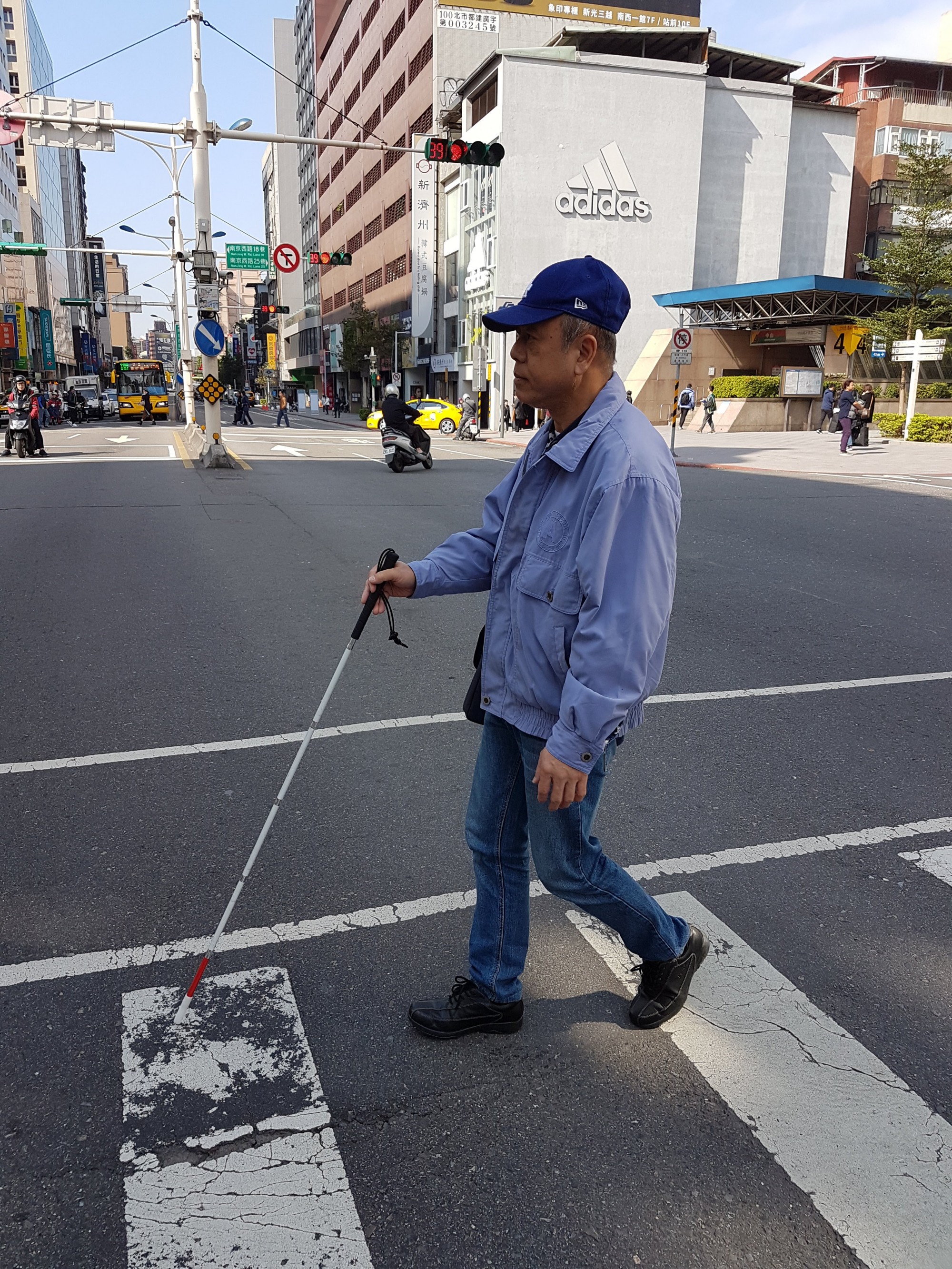 視障者手持白手杖行走於行人穿越道上